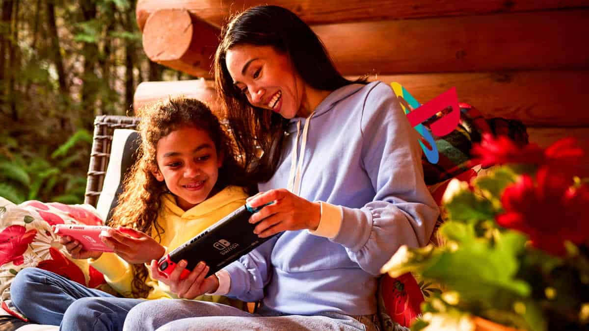 Playstation imgae of a Sony PlayStation simbol peeking over the shoulder of a parent and child playing on Switch handheld console